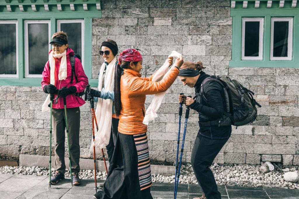 NamcheMountain Lodges of Nepal - Namche的一群三人在滑雪板上,在一座建筑前