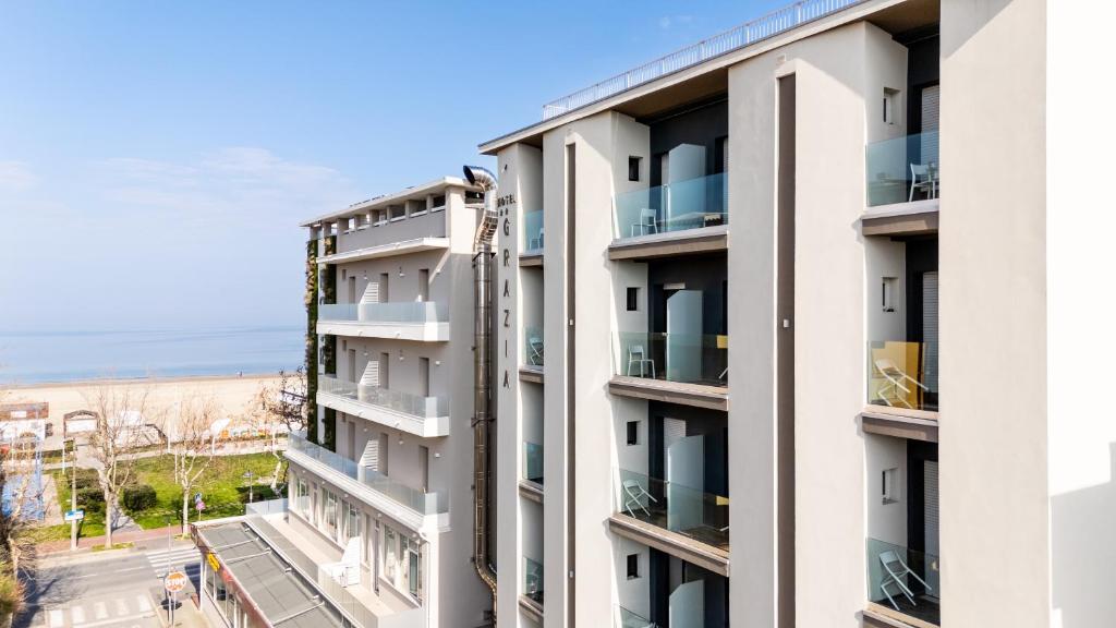 里乔内Hotel Grazia Riccione的公寓大楼设有阳台,其背景为大海