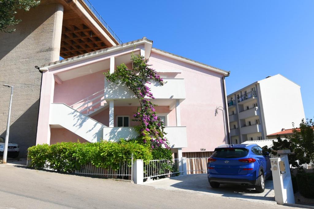 伯德古拉瓦登诺威公寓酒店的停在粉红色建筑前面的蓝色汽车