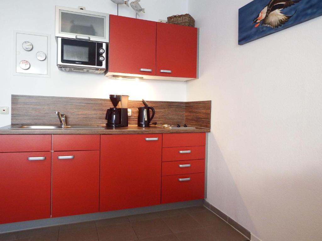 奥斯赛拜-屈隆斯博恩Yachthafenresidenz-Wohnung-8106-9412的一间带红色橱柜和微波炉的厨房