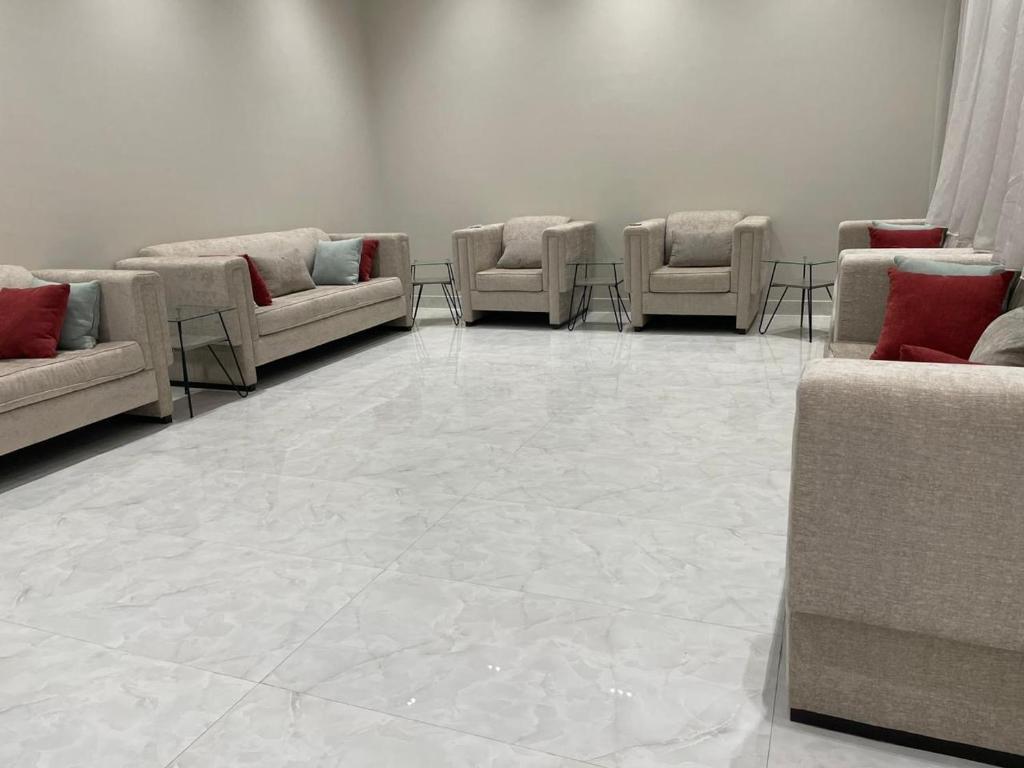 Bawḑahشالية الفهد的一间配有沙发和椅子的等候室,位于瓷砖地板