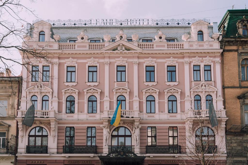 利沃夫Grand Hotel Lviv Casino & Spa的前面有旗帜的粉红色建筑