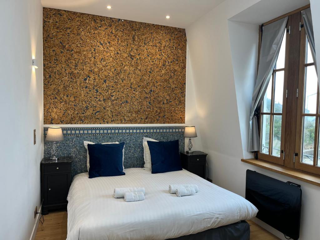 迪纳尔Le Royal XIX Dinard vue mer luxe的一间卧室配有一张带蓝色枕头的大床