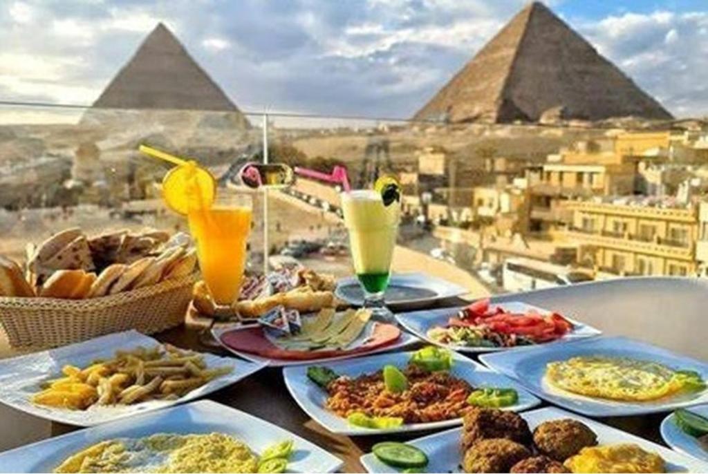 开罗Carpet Alaadein Pyramids view的一张桌子,上面放着食物和金字塔