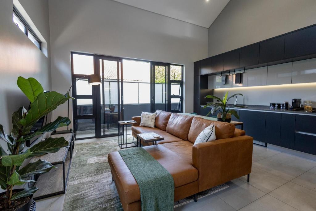 比勒陀利亚Luxurious Upmarket Apartment的一间带棕色沙发的客厅和一间厨房