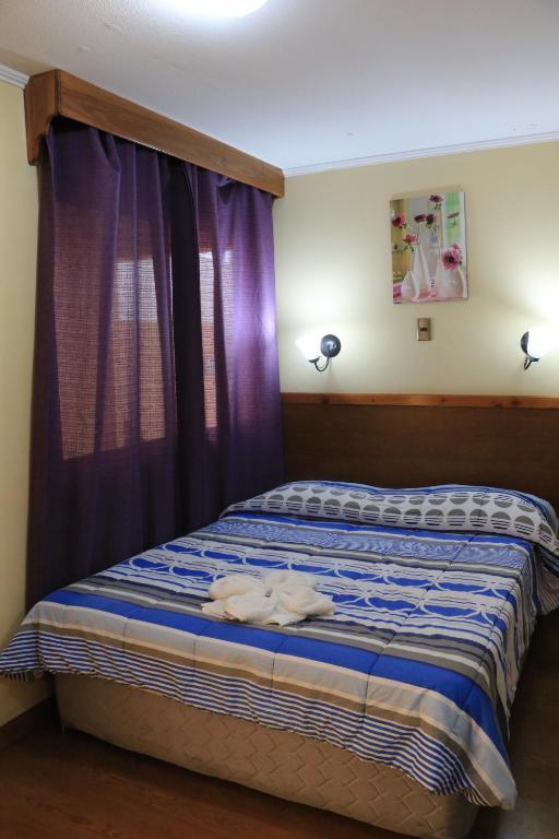 伊基克Hotel Garden Wilson的一间卧室配有一张紫色窗帘的床