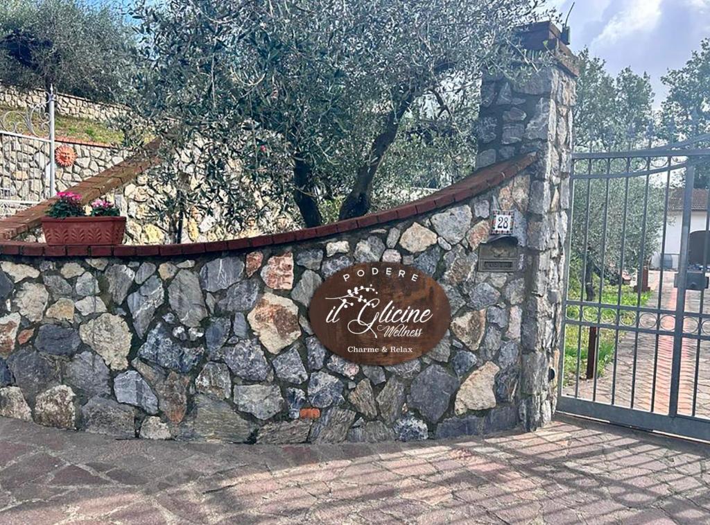 FresonaraPodere il Glicine Wellness Charme & Relax的围栏上带有标志的石墙