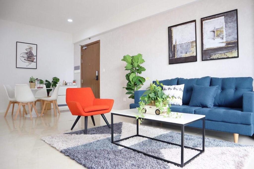 胡志明市Delightful Apartment - Masteri Millennium - FREE Infinity Pool的客厅配有蓝色的沙发和红色的椅子
