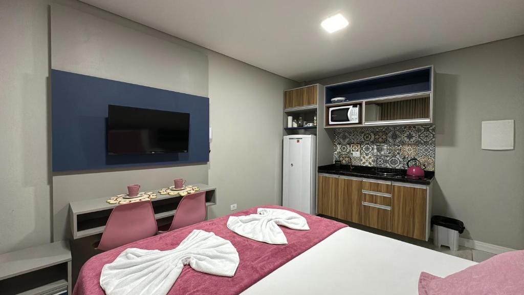 库里提巴14- Studio decorado com ótima localização!!!的一间卧室配有一张床、一张书桌和一台电视。