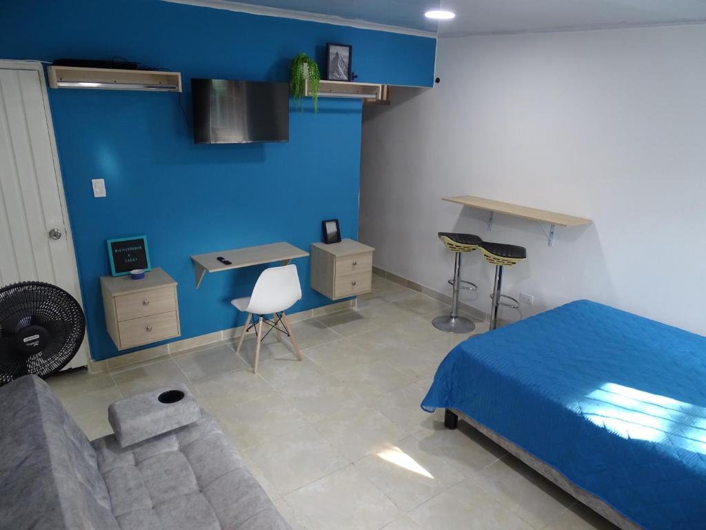 卡利Apartamento en el sur de Cali的一间卧室设有蓝色的墙壁、一张床和一张书桌