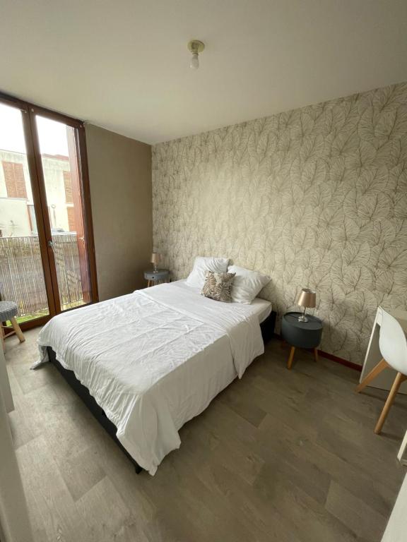 圣雅克德拉朗德CHARMANT APPARTEMENT AVEC GRANDE CAPACITÉ D’ACCUEIL的卧室配有一张白色大床和一堵墙