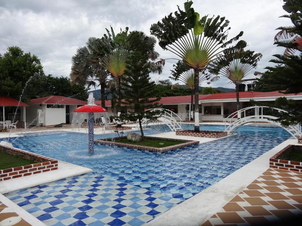 AguazulCENTRO VACACIONAL & HOTEL CAMPESTRE LAGO CENTER的一个带红色遮阳伞和棕榈树的游泳池