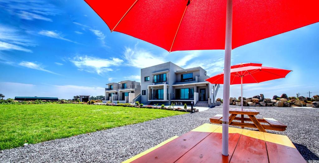 西归浦市博乐姆度假屋的一把红伞和房子前面的长凳