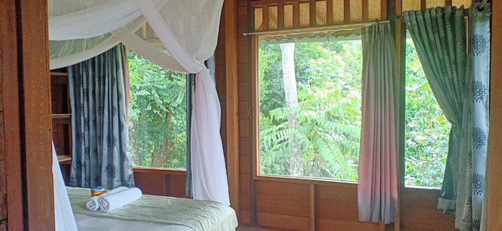 武吉拉旺On The Rocks Bungalows, Restaurant and Jungle Trekking Tours的一间卧室设有一张床和一个大窗户
