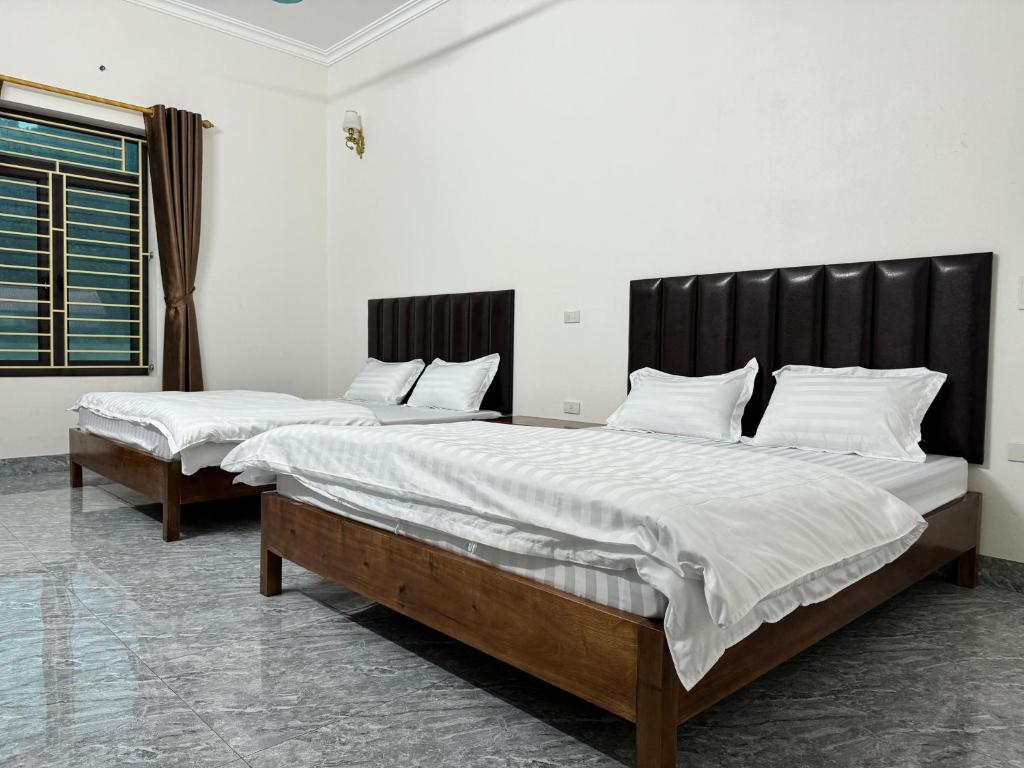 Nho QuanHotel Minh Thắng的配有2张床的带白色床单和枕头的客房