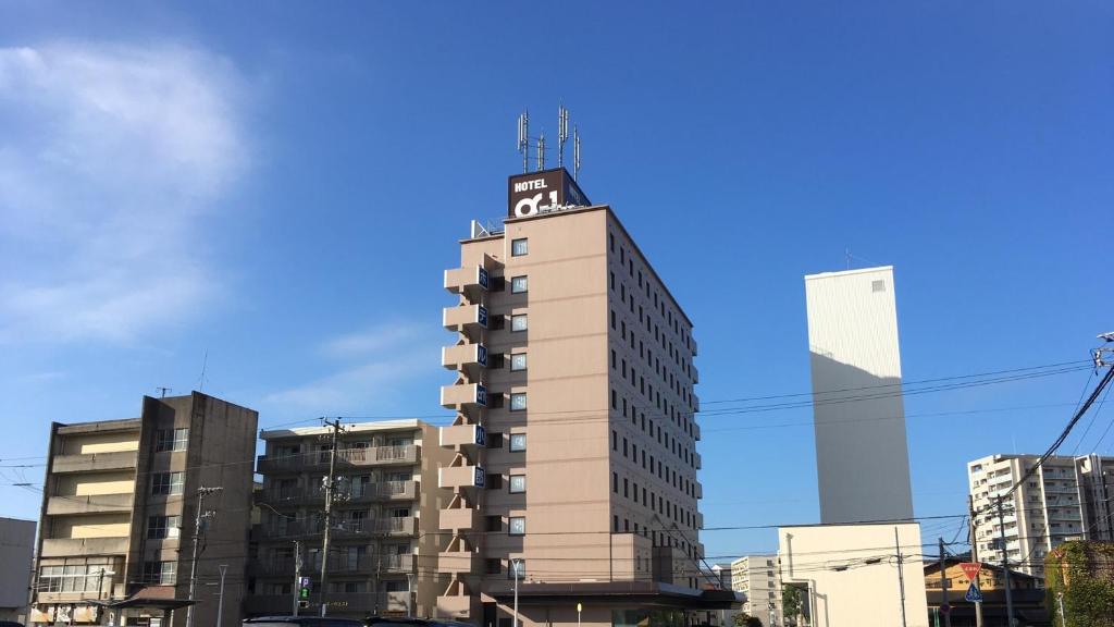 山口Hotel Alpha-One Ogori的一座高大的建筑,上面有标志