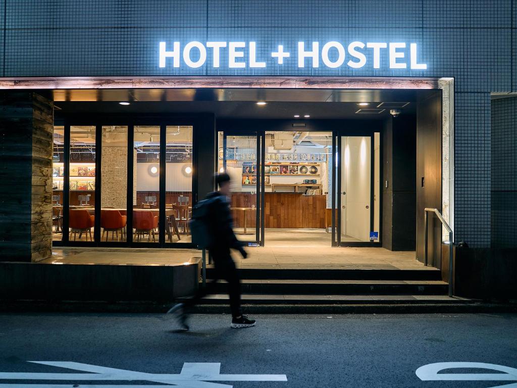 川崎Hotel Plus Hostel TOKYO KAWASAKI的在酒店旅馆前行走的人