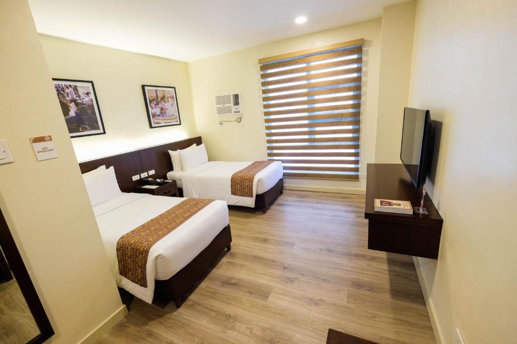 宿务Cebu Quincentennial Hotel的酒店客房设有两张床和一台平面电视。