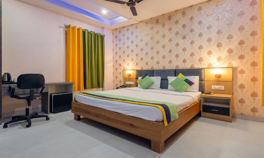 勒克瑙Treebo Trend Shakuntalam的一间卧室配有一张床、一张桌子和一把椅子