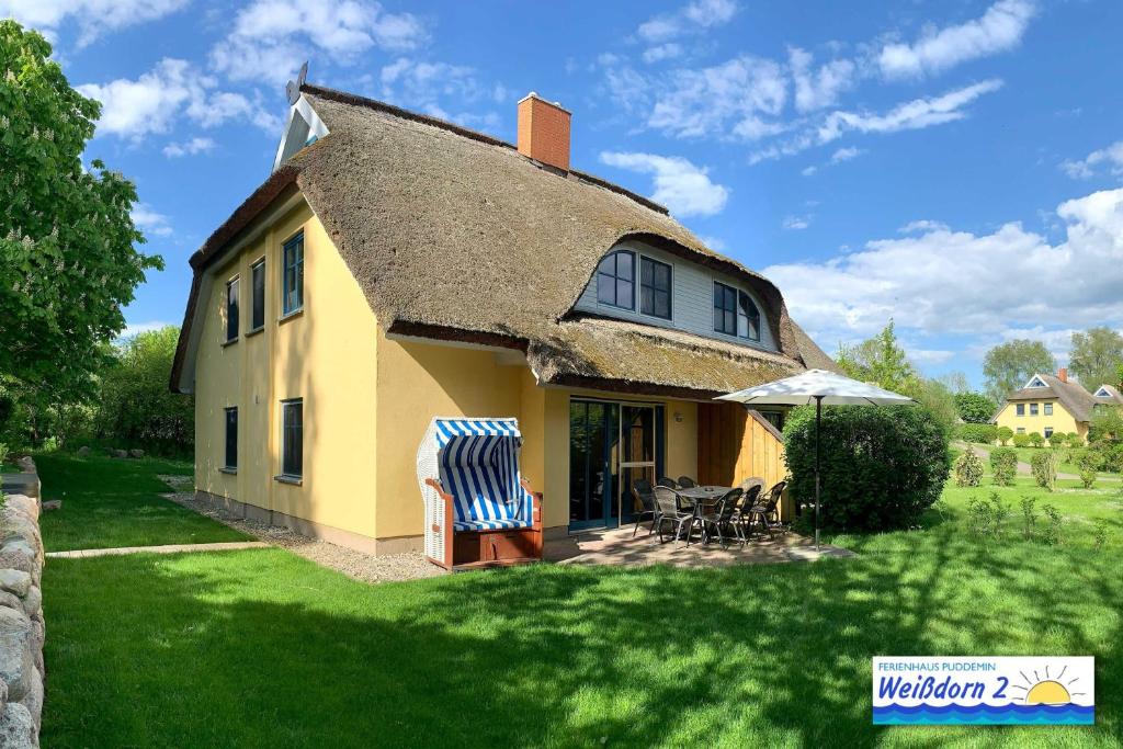 布德明Familienfreundliches Reetdachhaus Weissdorn 2的庭院上带茅草屋顶的黄色房子