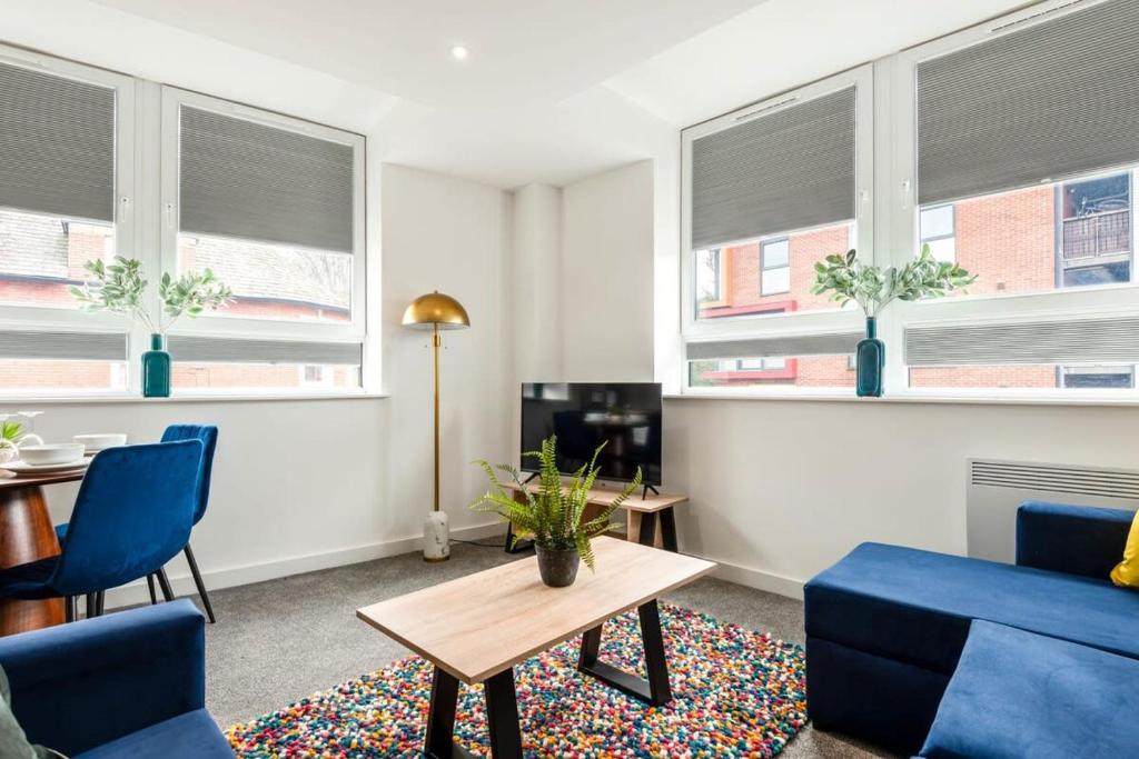罗瑟勒姆Bright 1 Bedroom Apartment in Central Rotherham的客厅设有蓝色的椅子、桌子和窗户
