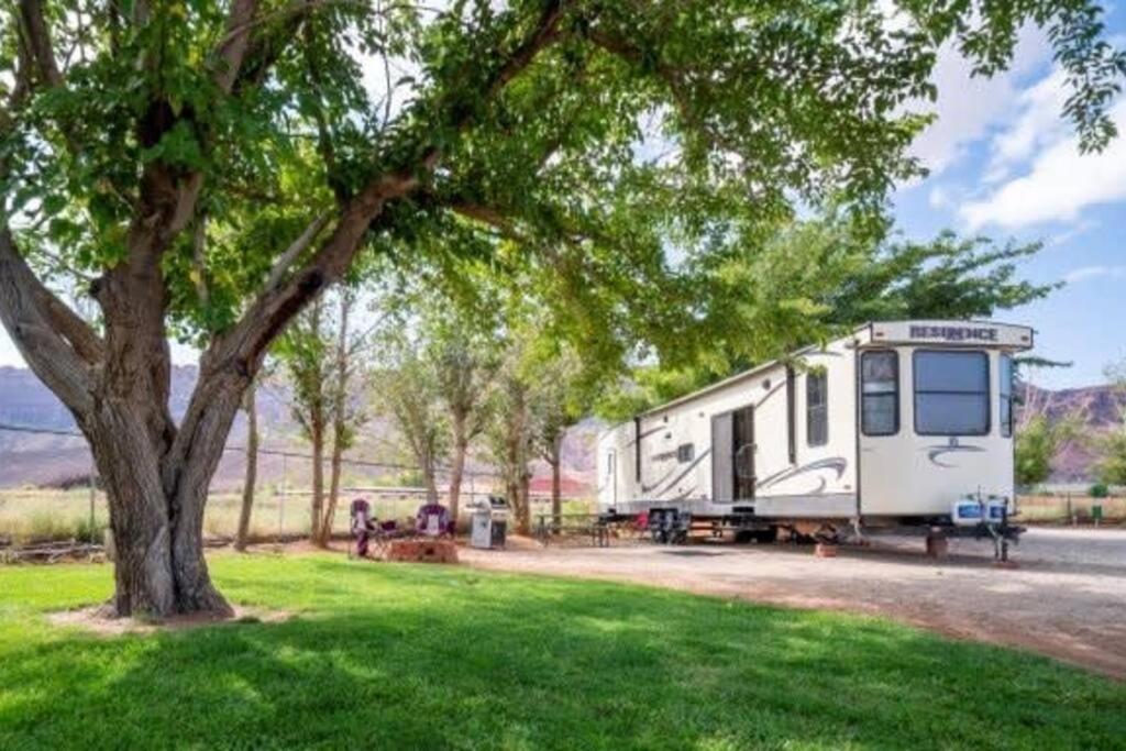 摩押Moab RV Resort Outdoor Glamping Destination RV OK40的停在树下田里的拖车