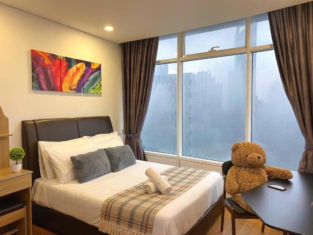 吉隆坡KL Cozy Apartment At Vortex KLCC的一间卧室,配有一张桌子上带泰迪熊的床