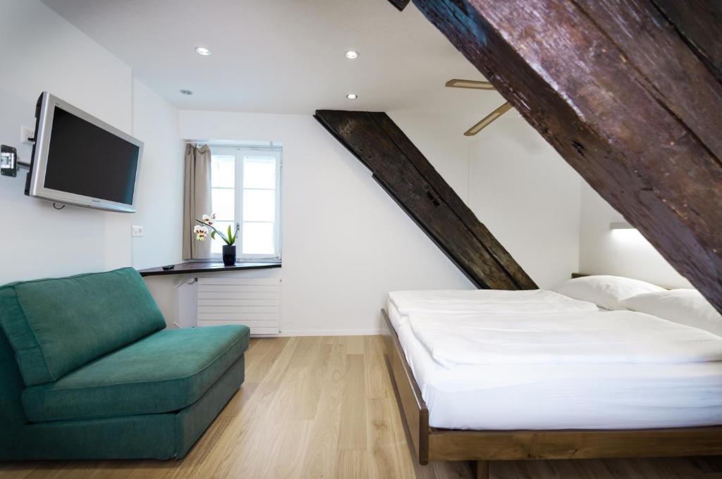 卢塞恩罗斯里宾馆的一间卧室配有一张床和一把绿色椅子