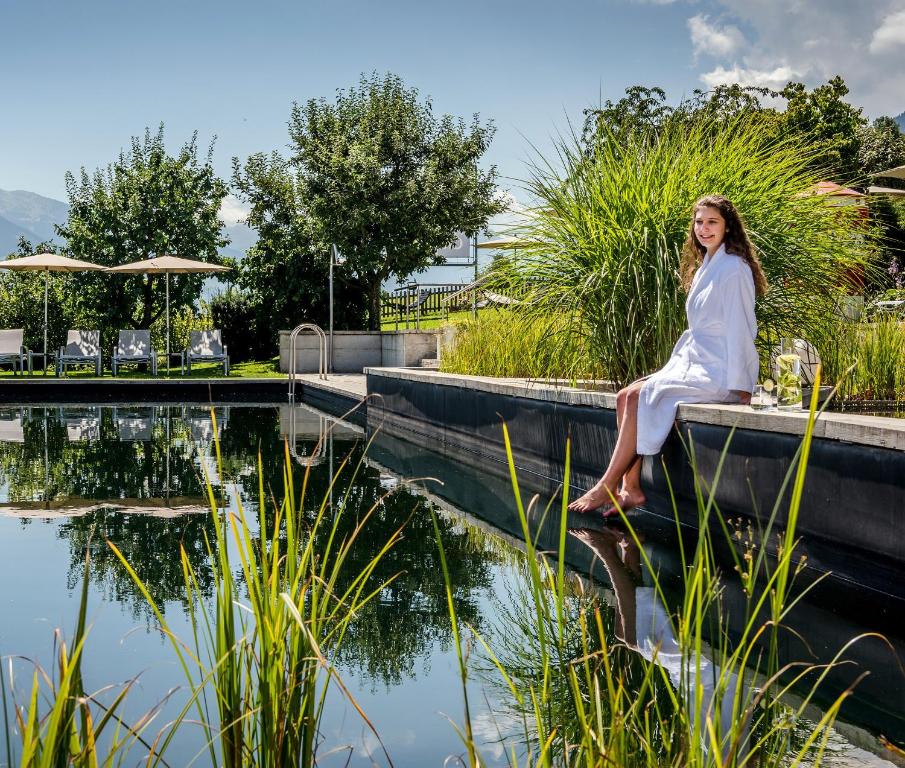 菲根Gardenhotel Crystal - 4 Sterne Superior的坐在池塘旁的树 ⁇ 上的女人
