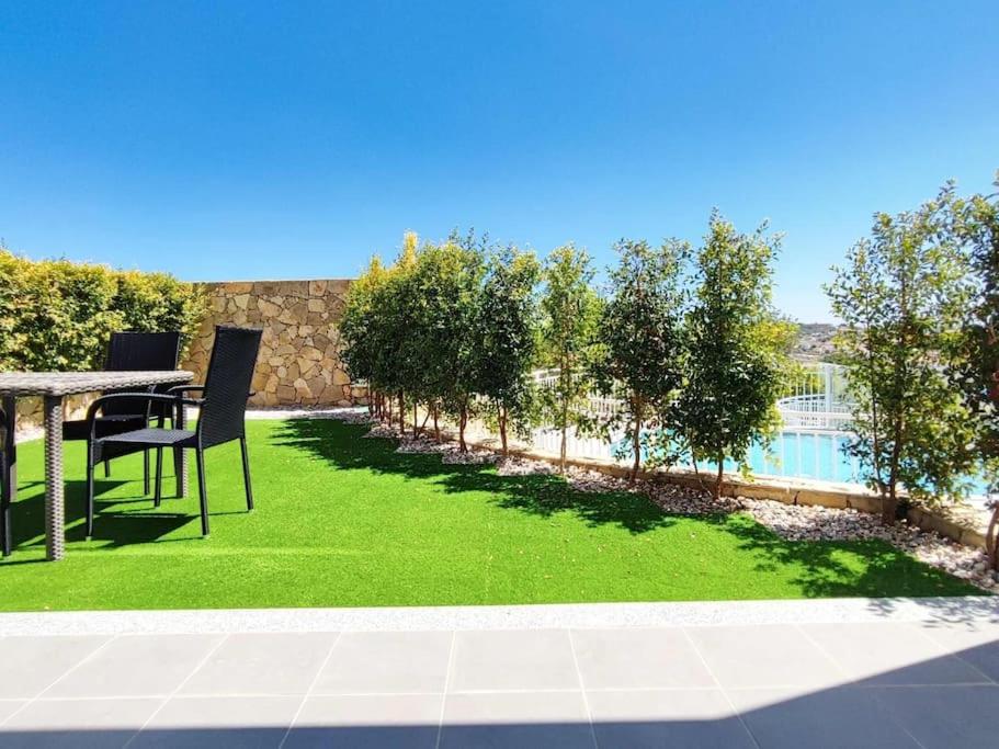 阿尔布费拉Vistas Mar Villas D - Sea View & Garage & Pool and Garden的一个带桌椅的庭院和一个绿色草坪