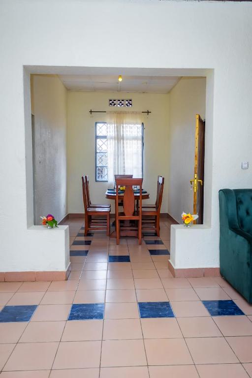 鲁亨盖里Rhoja homes的一间铺有瓷砖地板并配有桌椅的用餐室
