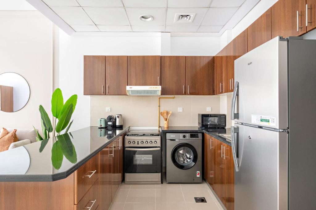 迪拜Silkhaus Modern Studio Near Silicon Central Mall的厨房配有木制橱柜、洗衣机和烘干机