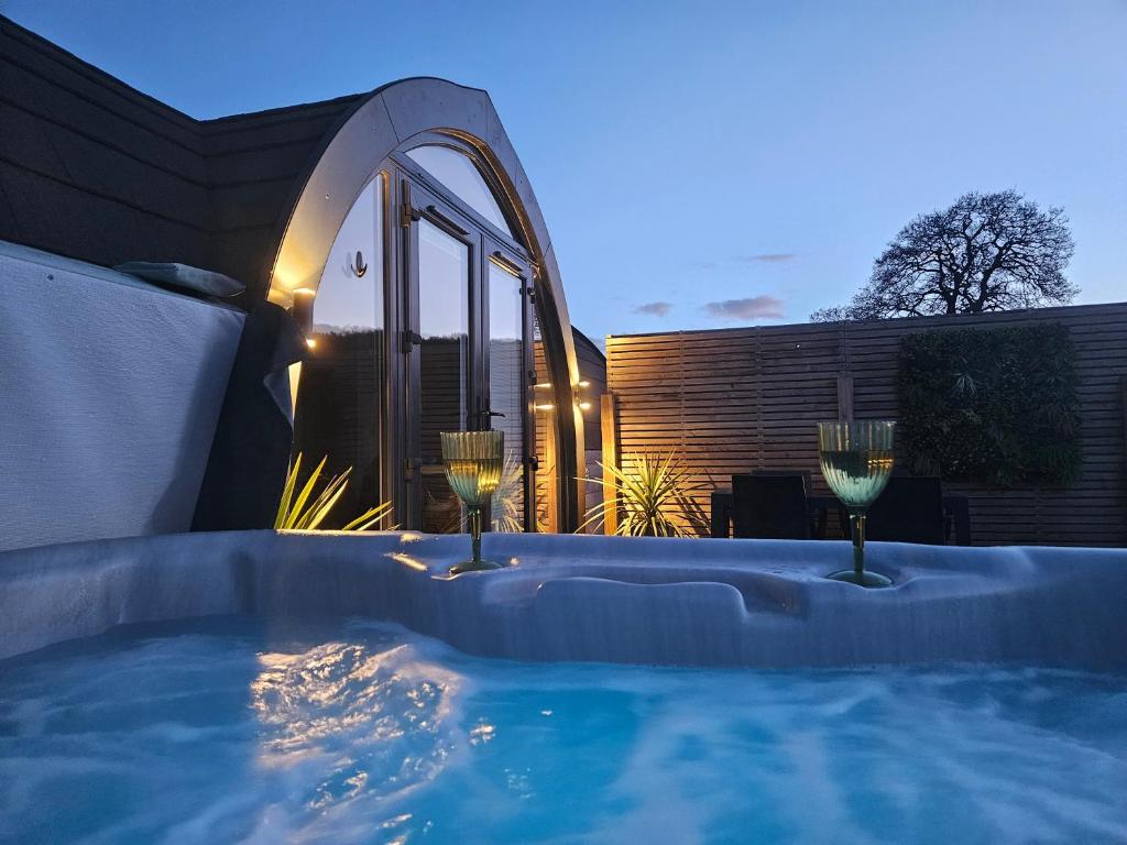 什鲁斯伯里EASTRIDGE GLAMPING的后院的热水浴池,配有2杯葡萄酒