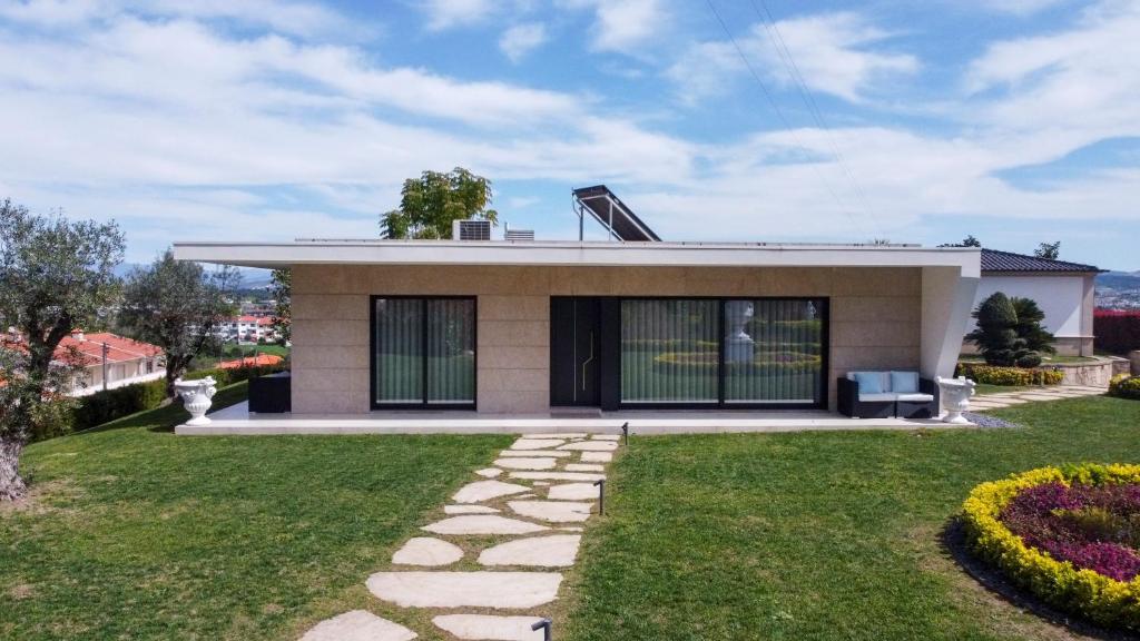 吉马良斯Casa Tranquilidade - Casa moderna com piscina的前面有草坪的小房子