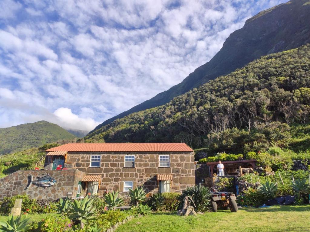 Fajã da Caldeira de Santo CristoCaldeira Guesthouse的一座以山为背景的石头房子