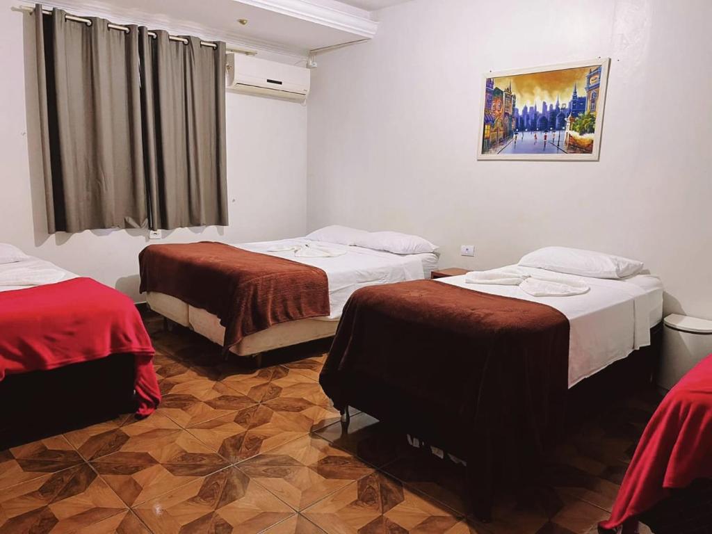 伊瓜苏Pousada da Maira的一间设有两张床的客房,墙上挂着一幅画