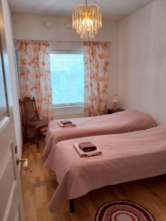 LoimaaHannelen Varakoti的一间卧室设有两张床、一个吊灯和一个窗户。