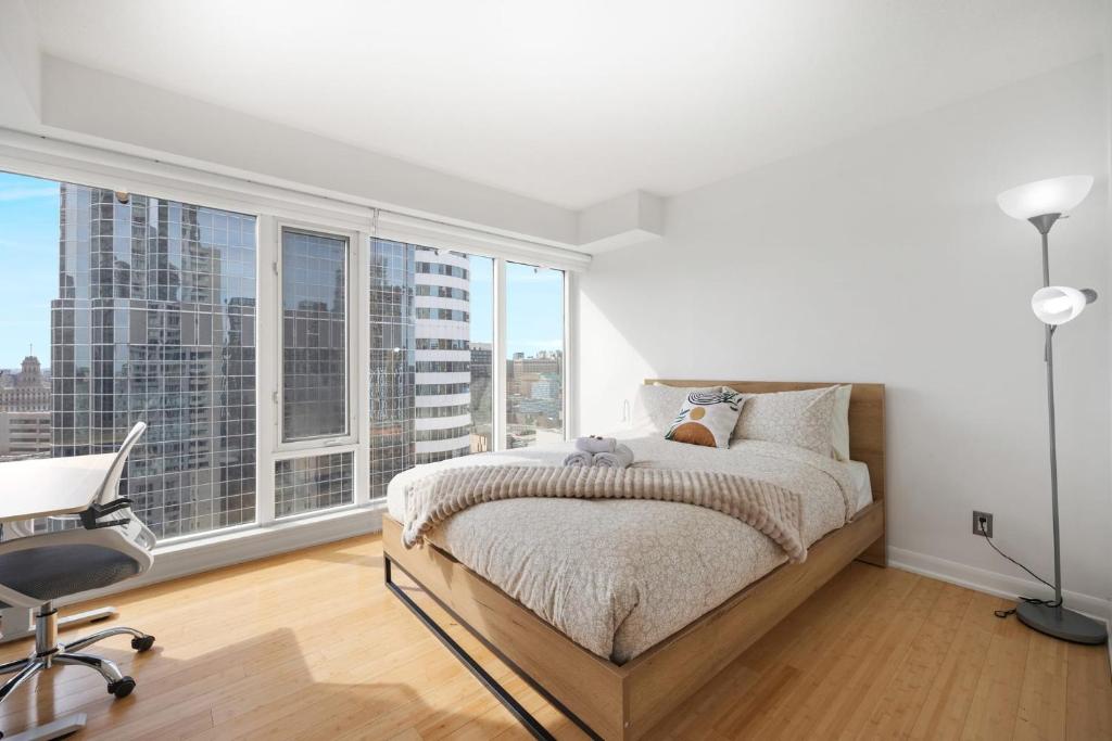 多伦多Modern 2-Bedroom Condo w Floor to Ceiling Windows的卧室配有一张床、一张书桌和窗户。