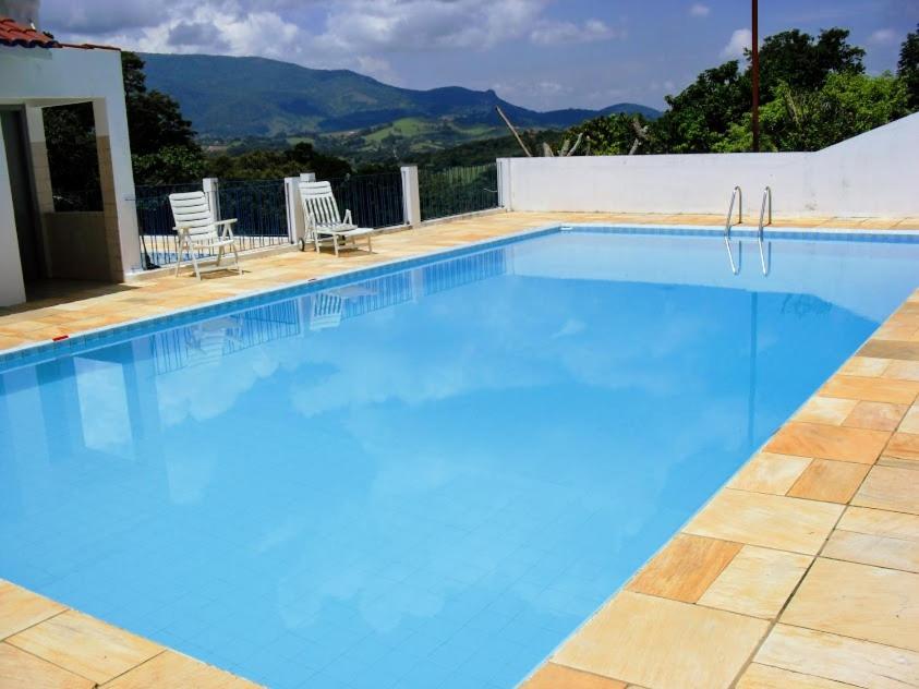 伊克斯雷玛Sua casa na Serra da Mantiqueira. 1h de SP的一个带两把草坪椅的大型蓝色游泳池