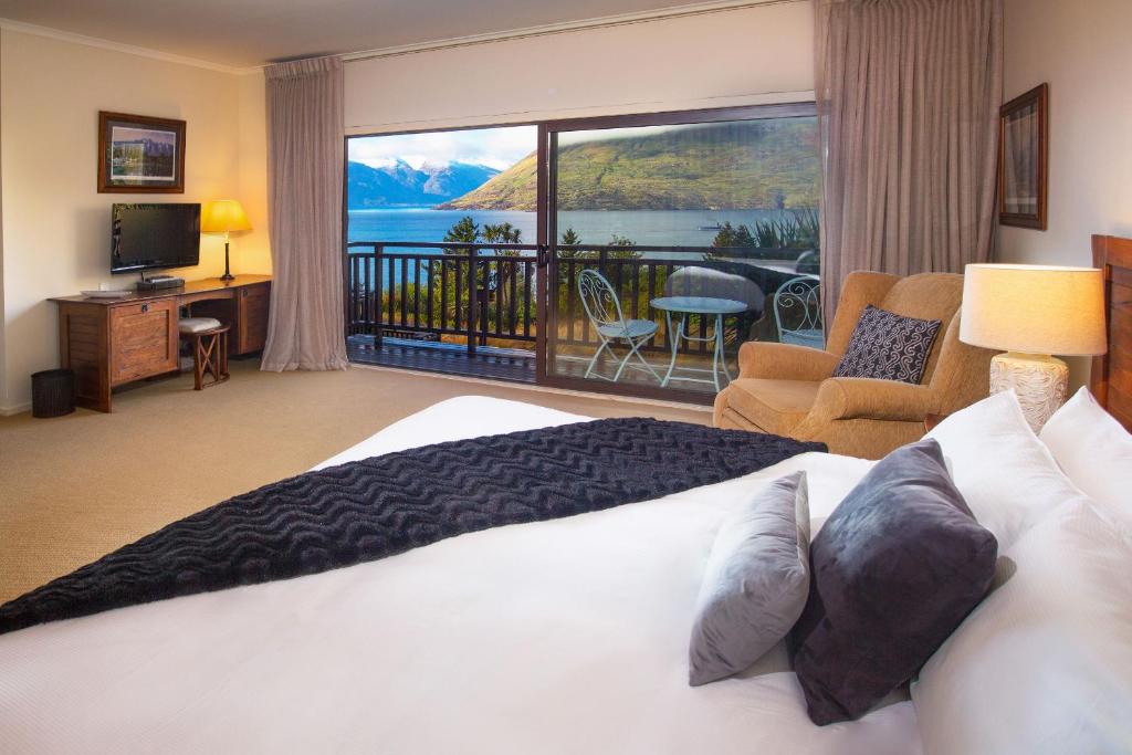皇后镇Hidden Lodge Queenstown的一间卧室设有一张床和一个美景阳台