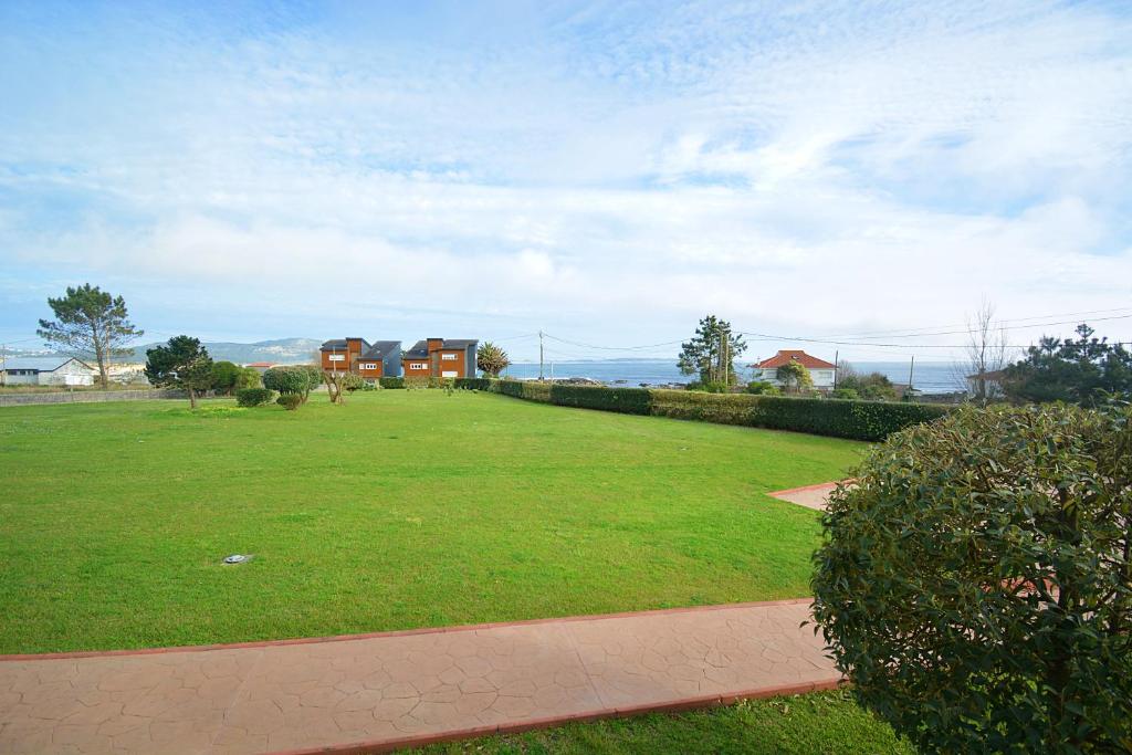 里贝拉Apartamento con jardín en Playa de Corrubedo的一座大草场,有房子的背景