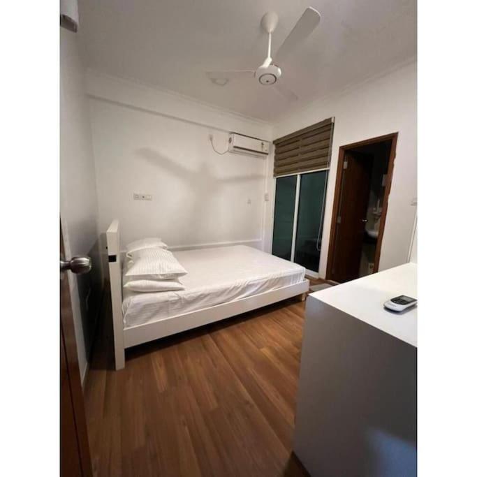 马累Ocean Apartments Hulhumale (Lot 10819)的一间卧室配有一张铺有木地板的白色床单。