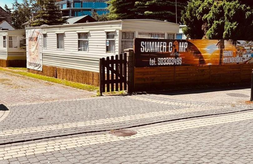 梅尔诺SummerCampMielno Domki Holenderskie的建筑物前的栅栏上的标志