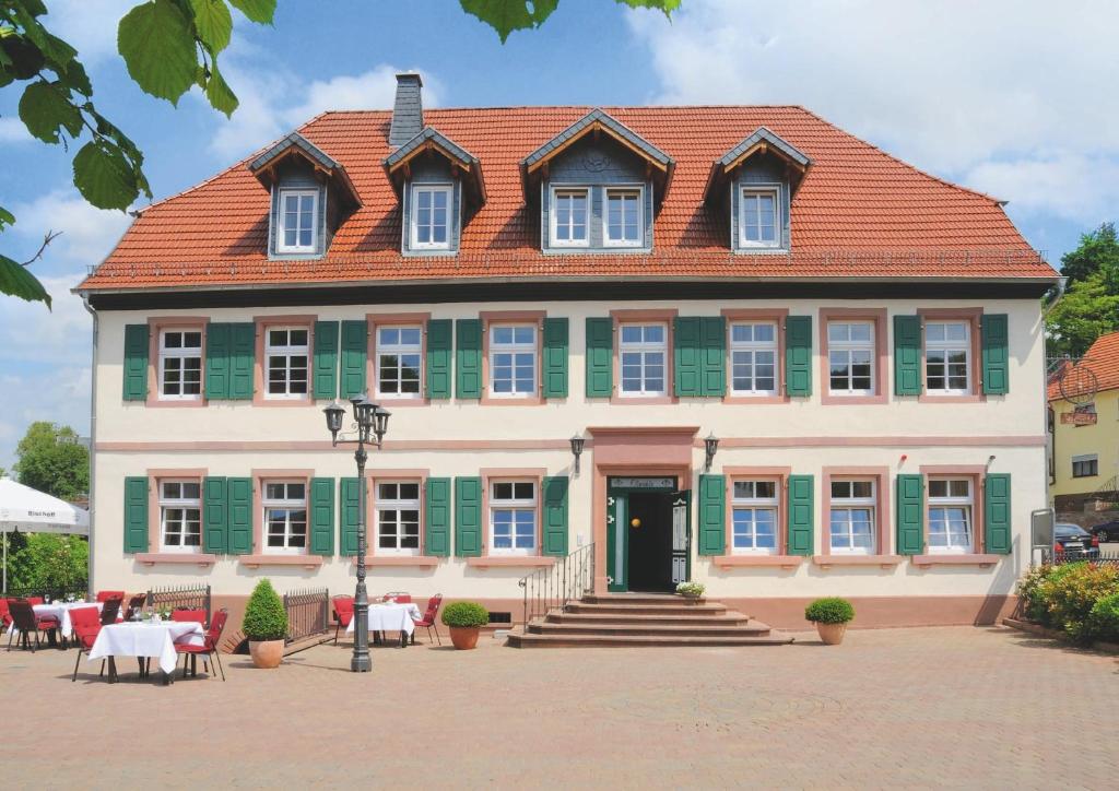 兰施图尔奥姆勒餐厅酒店的一座大型房屋,设有红色屋顶和绿色百叶窗