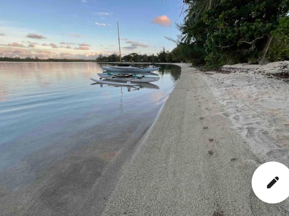 PareaLes pieds dans l’eau à huahine. Maison climatisée的两艘船坐在水体的岸边