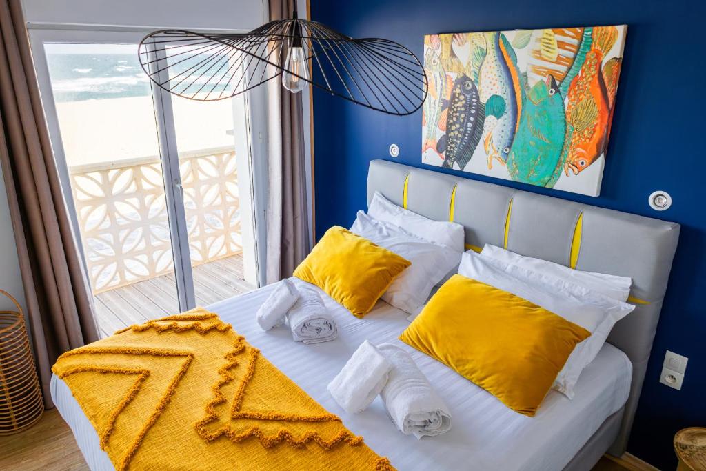 勒卡特HOTEL RESTAURANT LA COTE REVEE的蓝色卧室配有白色床和黄色枕头