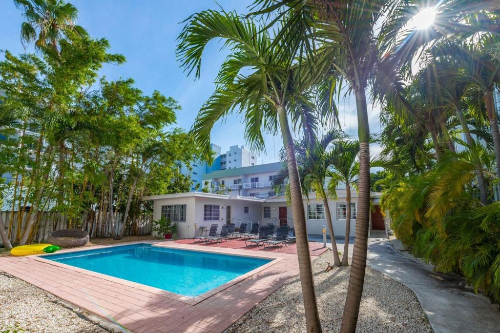 迈阿密海滩Casa Gaby Apartments Part of the Oasis Casita Collection的棕榈树屋前的游泳池