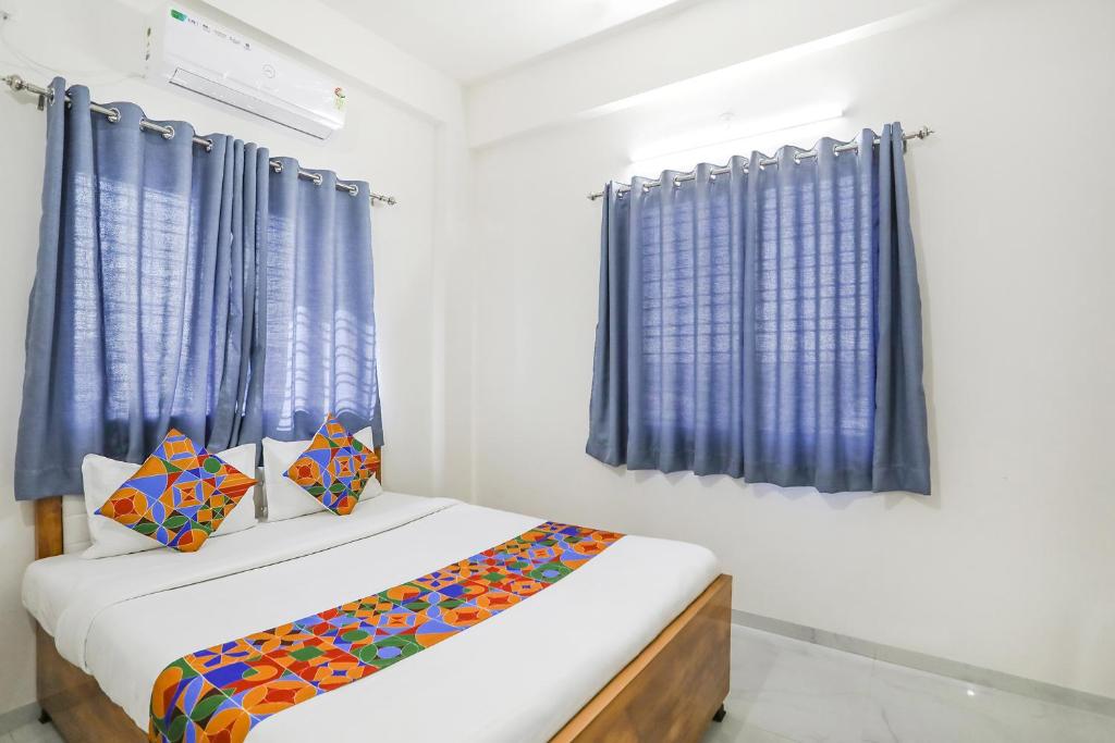 纳西克FabHotel Blue Ocean MNJ Resort的一间小卧室,配有蓝色窗帘和床