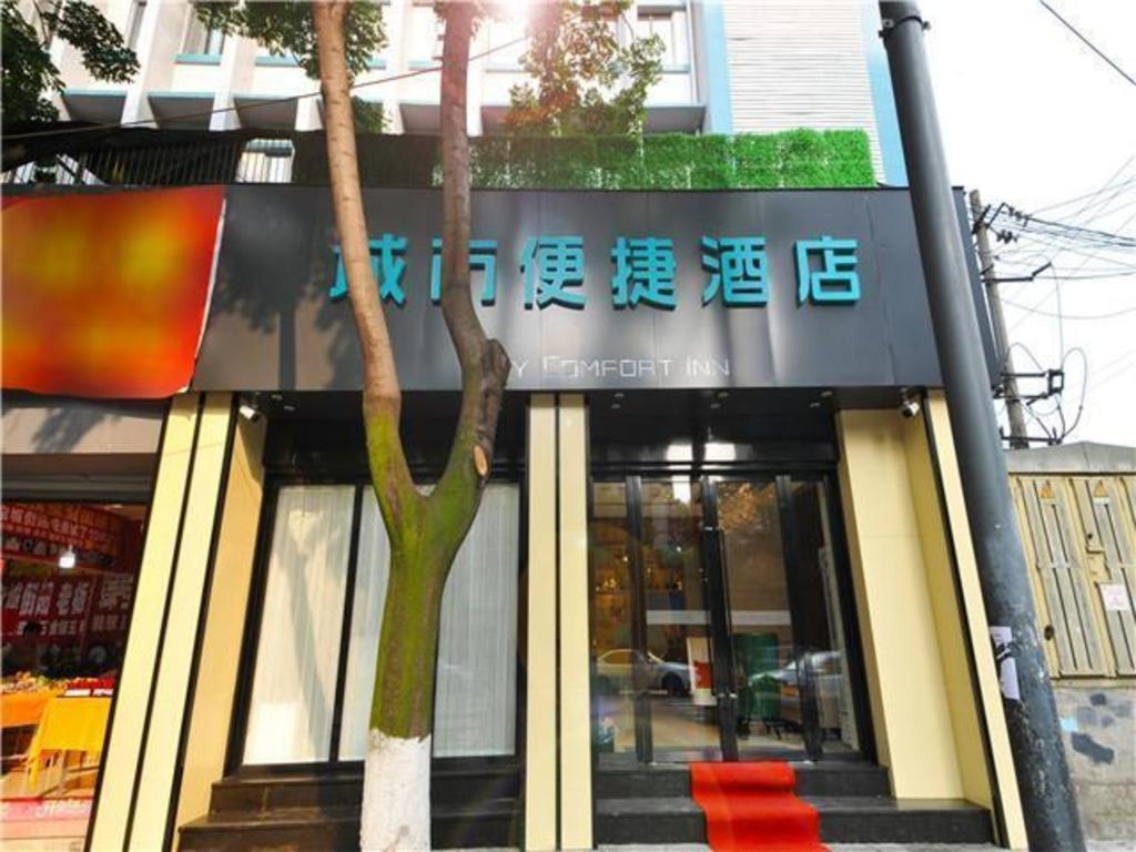 成都City Comfort Inn Chengdu Jinniu Wanda Liangjiaxiang Metro Station的前面有棵树的建筑
