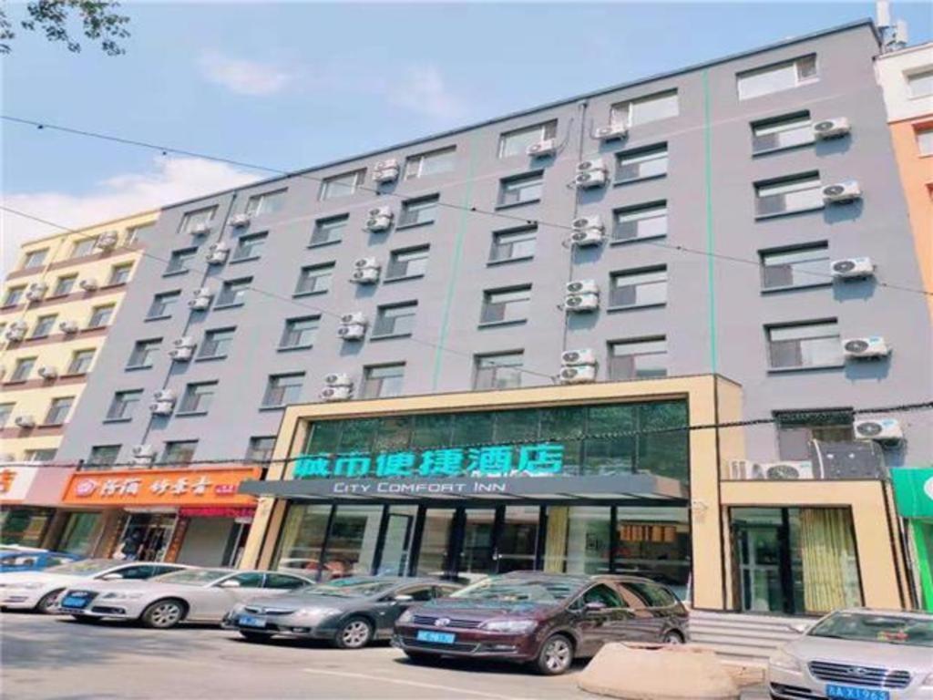 长春City Comfort Inn Changchun Wenhua Square Xi Zhonghua Road的一座大型建筑,前面有汽车停放